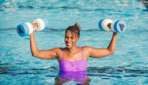 Person using aquatic dumbbells during a pool exercise for water resistance training and upper-body strength.