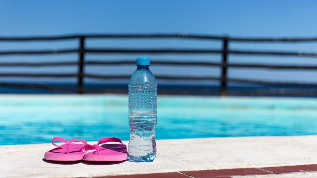 Can you sweat while swimming? Water bottle beside a swimming pool during aqua aerobics and swimming workout