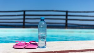 Can you sweat while swimming? Water bottle beside a swimming pool during aqua aerobics and swimming workout