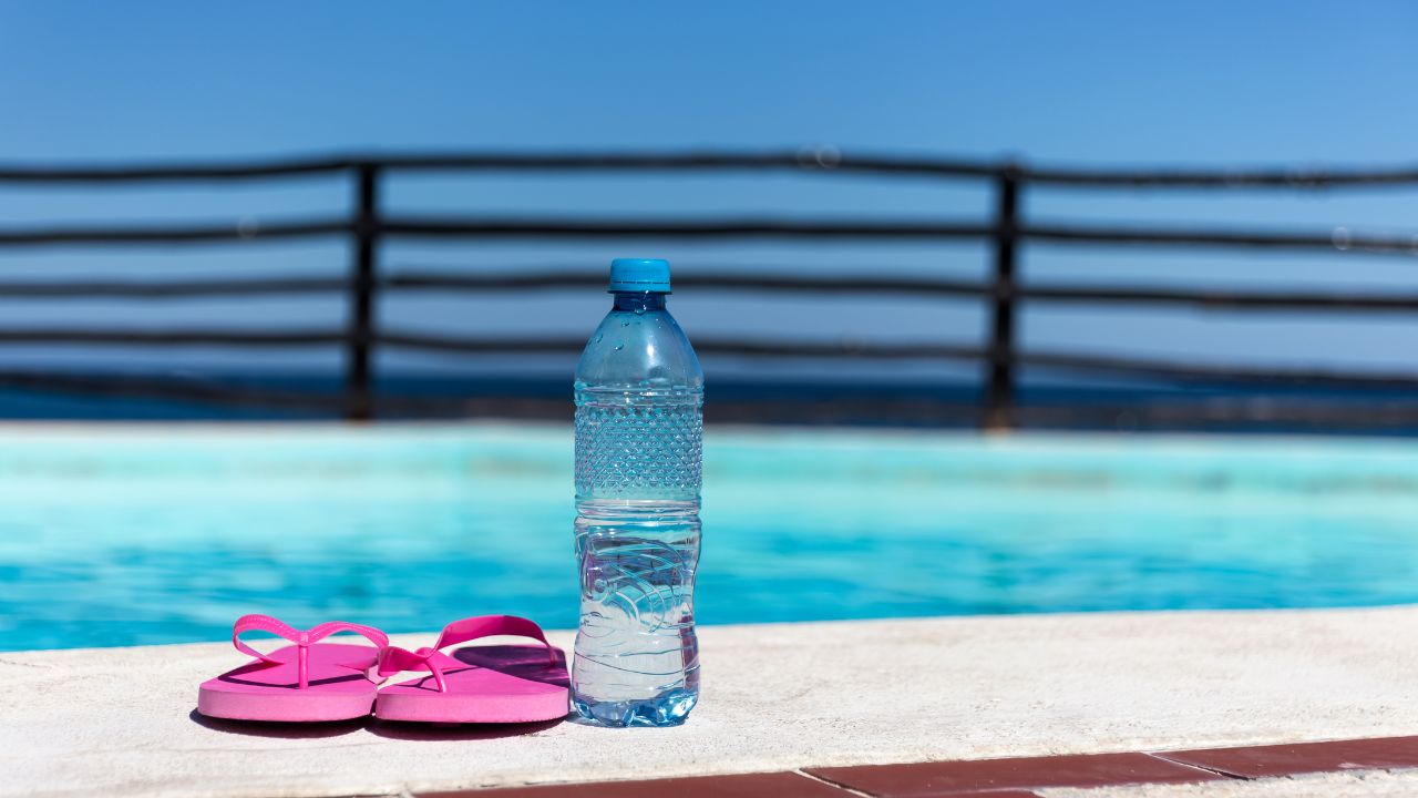 Can you sweat while swimming? Water bottle beside a swimming pool during aqua aerobics and swimming workout