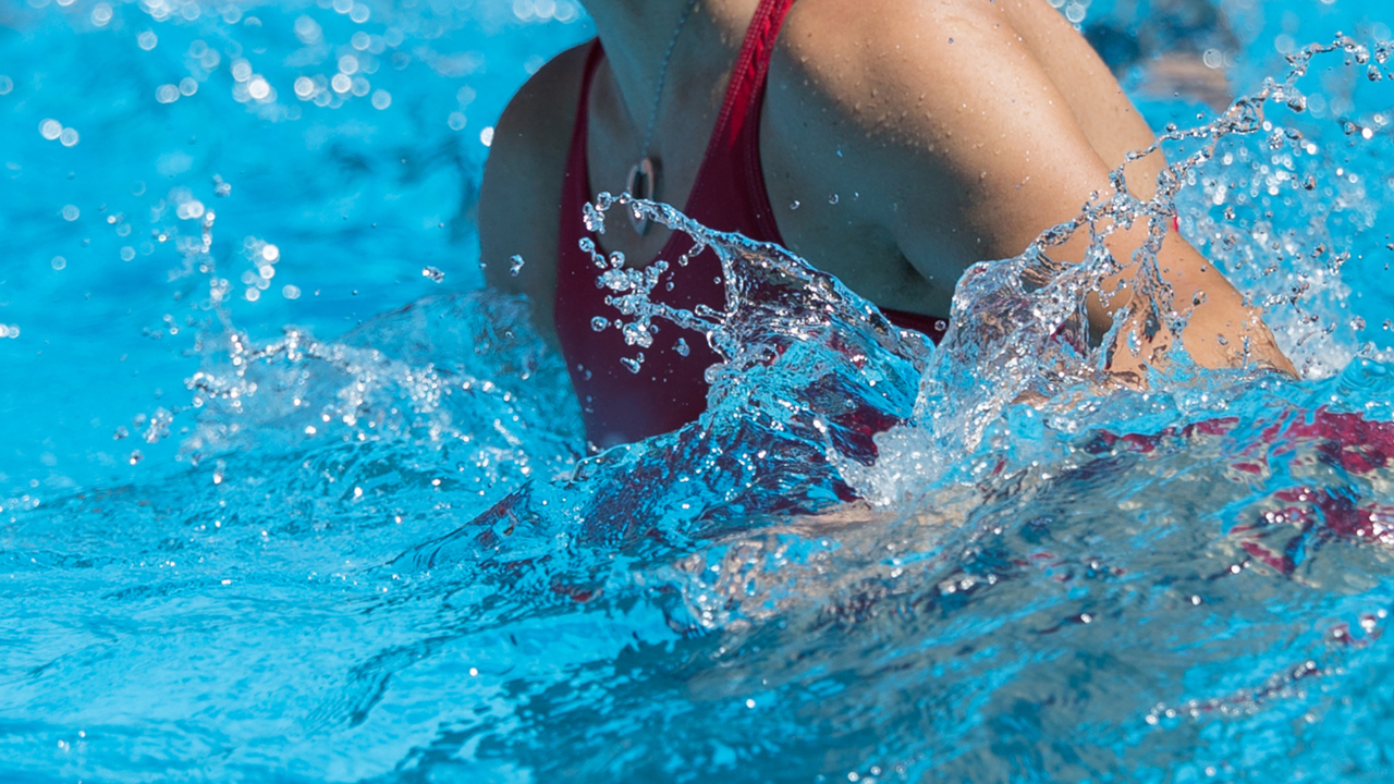 Person performing water exercise in a pool with splashing water, showing aquatic core stability and resistance training.