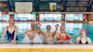 Adults participating in water resistance training and aquatic fitness exercises in a swimming pool