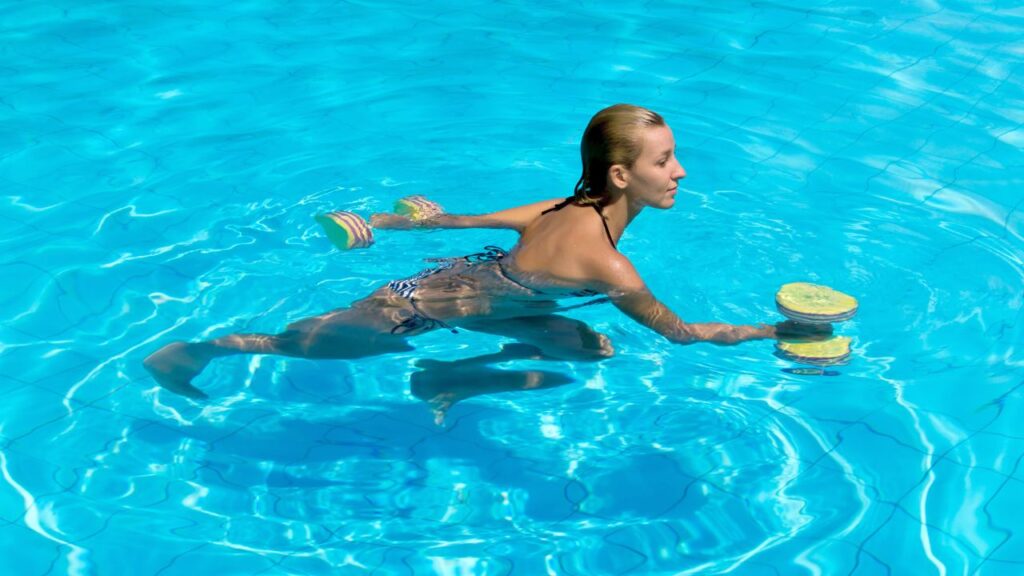 Woman exercising underwater with a pool noodle during a low-impact water workout