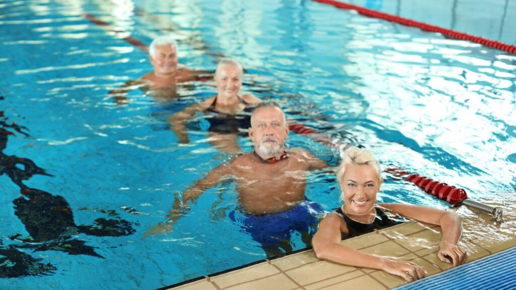 Older adults standing in a swimming pool during a water movement or swimming class for strength, mobility, and healthy aging.